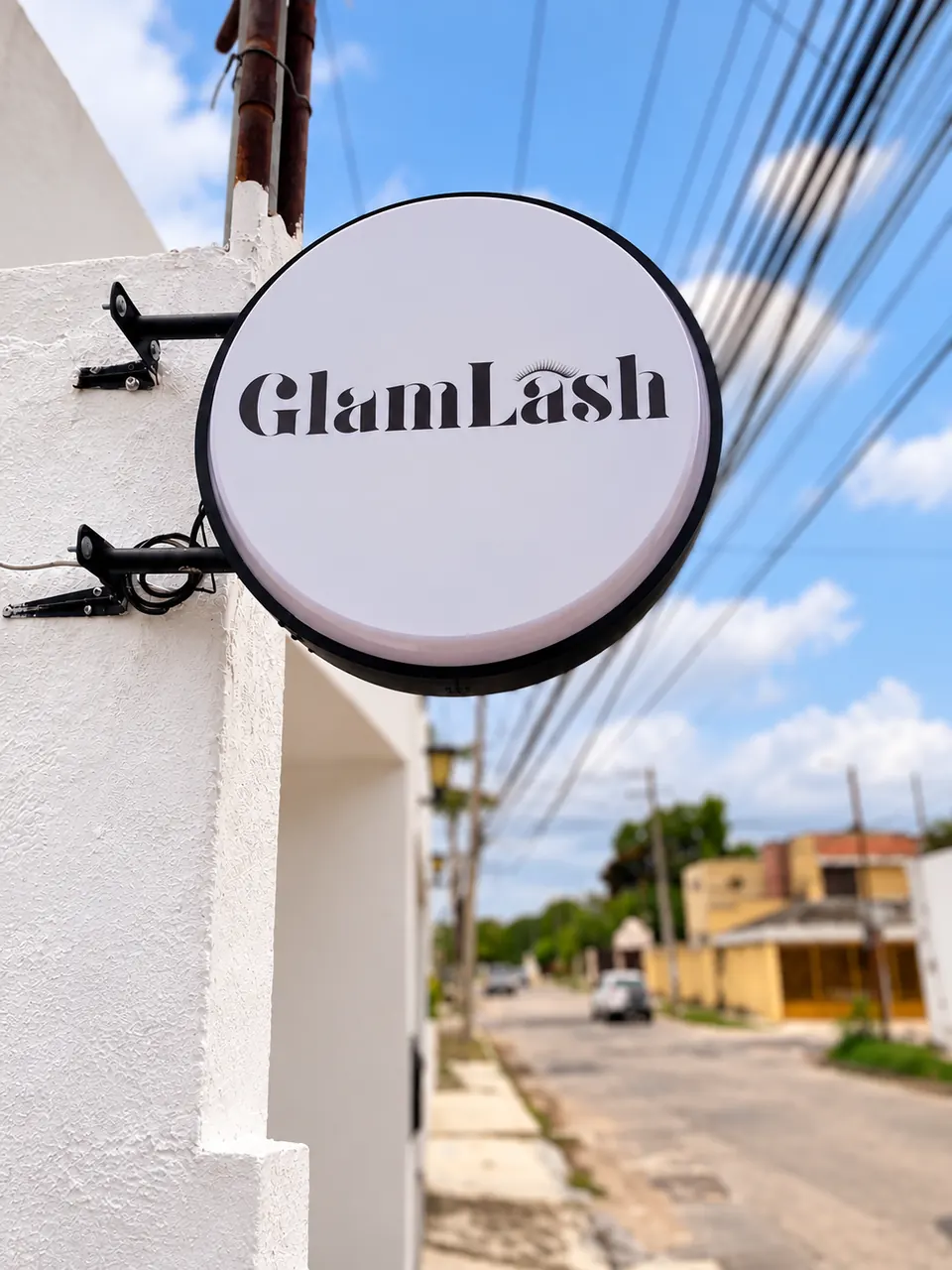 Letrero circular de Glam Lash en la fachada, vista a la calle